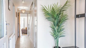 A hallway with a potted plant, a bench, and a door leading to a room. - Spacious 4-bed, Free Parking, Short or Long Stays (Manchester)