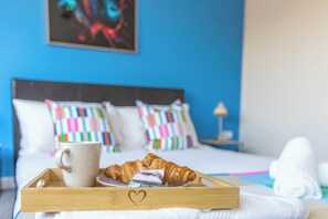 A bed with colorful pillows, a white mug, and croissants on a tray. - Spacious 4-bed, Free Parking, Short or Long Stays (Manchester)