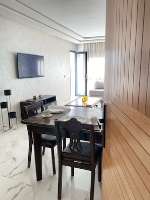 Enjoy meals in this dining area with a large TV and sliding glass door leading to a balcony with an outdoor view.