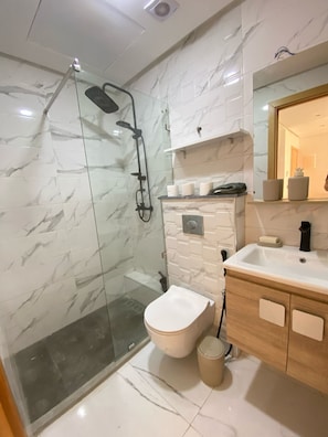 Enjoy a refreshing shower in the sleek bathroom with a glass-enclosed shower, handheld showerhead, and vanity with sink.