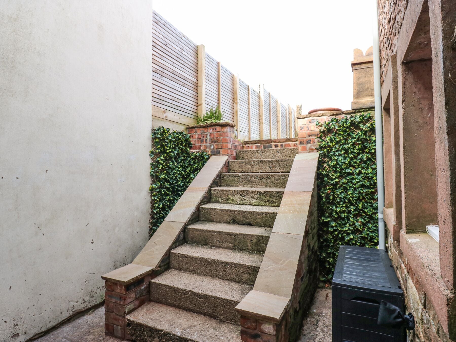 Eine schmale Treppe mit Steinstufen und Ziegelmauern, die zu einer höheren Ebene führt.