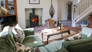 A cozy living room with a fireplace, green sofas, a wooden coffee table, and a staircase.
