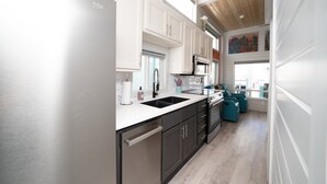 A modern kitchen with white cabinets, stainless steel appliances, and a view to the living area. - Lucky Break, River Views at Roadrunner Resort (Parker)