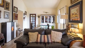 A cozy living room with a leather sofa, a fireplace, and various framed pictures on the walls.