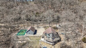 A two-story house with a deck and a green tennis court. - Available Labor Day Wkd, Lake Front, Pickleball! (Garfield)