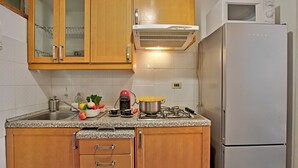 A kitchen with wooden cabinets, a stainless steel sink, a microwave, and a refrigerator. - Bardonest - Central Studio in Bardonecchia (Bardonecchia)