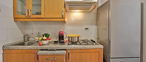 A kitchen with wooden cabinets, a stainless steel sink, a microwave, and a refrigerator.