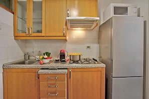A kitchen with wooden cabinets, a stainless steel sink, a microwave, and a refrigerator. - Bardonest - Central Studio in Bardonecchia (Bardonecchia)