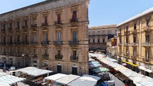 A street with multiple market stalls under canopies, surrounded by historic buildings with balconies. - LUCA'S GARDEN B&B IN CATANIA (Catania)