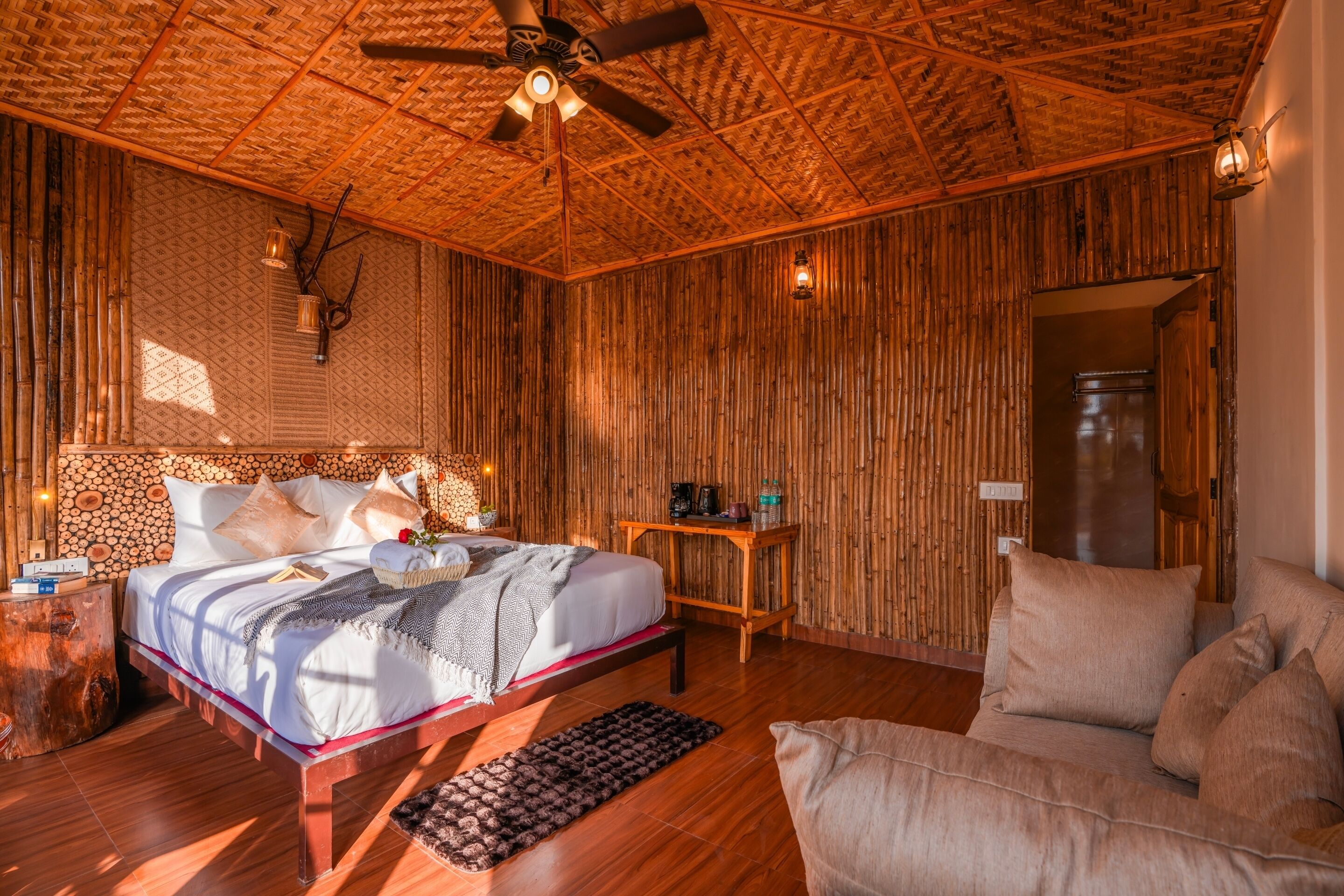 Quarto com cama, sofá, teto de madeira e parede com ripas verticais de madeira.
