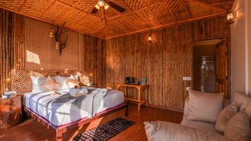 Quarto com cama, sofá, teto de madeira e parede com ripas verticais de madeira.