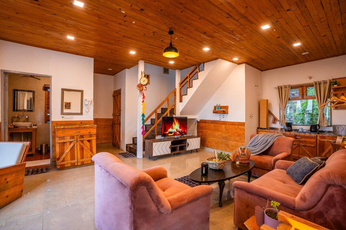 A cozy living room with a fireplace, plush seating, and a staircase leading to another level.