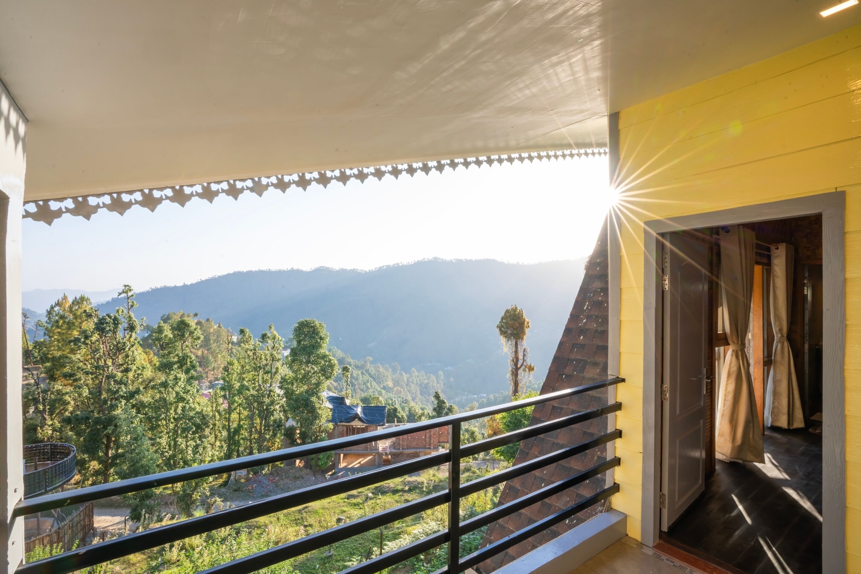 A balcony with a metal railing overlooking a mountainous landscape.