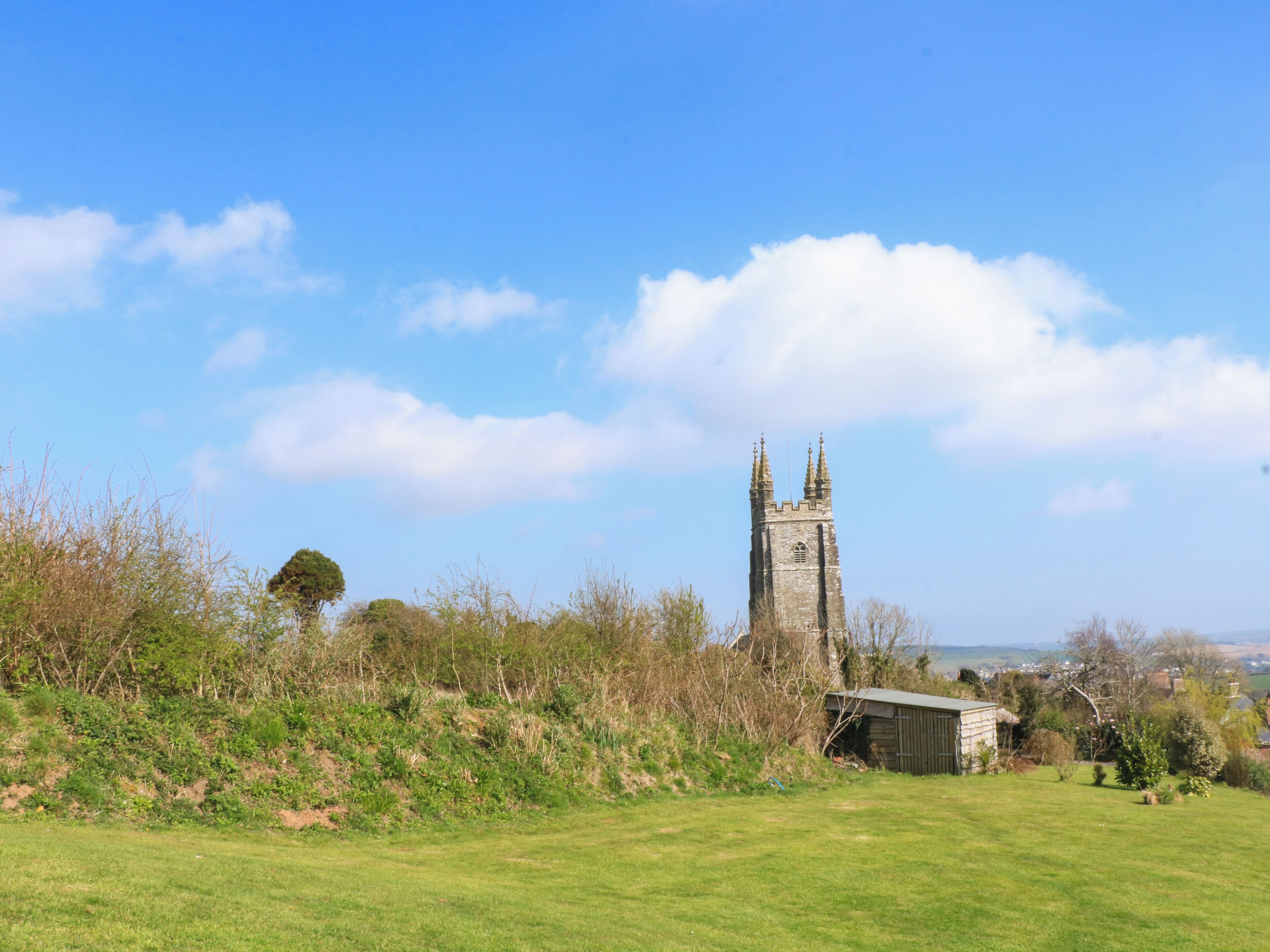 A tower with two spires, surrounded by greenery and a clear sky.