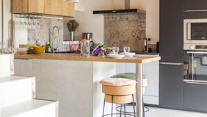 A modern kitchen with a central island, dark cabinetry, and pendant lighting. - Coudignac 1891 (Lagnes)