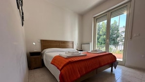 Un dormitorio con cama, mesita de noche, ventana con vistas y radiador.