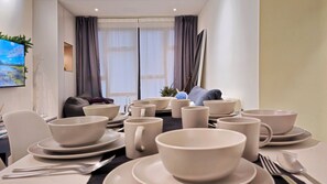 A dining area with multiple bowls and plates, a sofa, and a television displaying a nature scene.