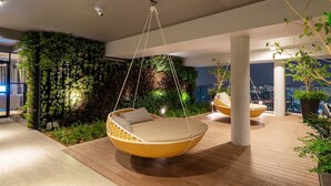 A modern outdoor seating area with hanging chairs and a lush vertical garden wall.