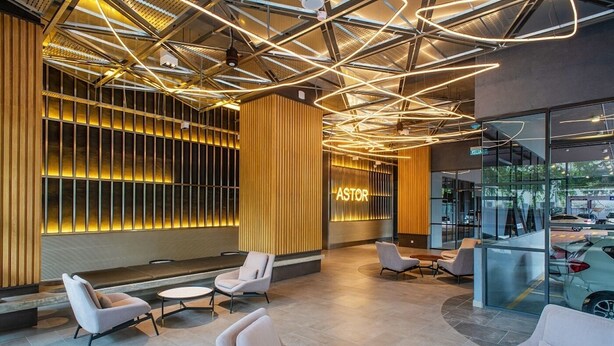 A modern lobby with a high ceiling, geometric lighting, and a seating area with sofas and a coffee table.