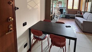 Un coin repas comprenant une table et des chaises, un canapé et une vue sur un balcon doté d’une balustrade.