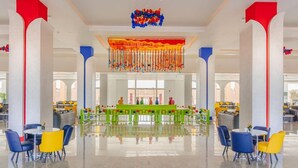Eine geräumige Lobby mit hohen Decken, einem zentralen grünen Tisch und bunten Stühlen.
