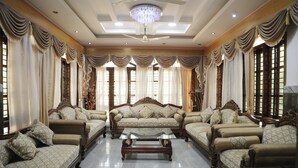 A spacious living room with a large sofa set, a glass coffee table, and elegant drapery. - Sugandhi Bhoja Shetty (Mangaluru)