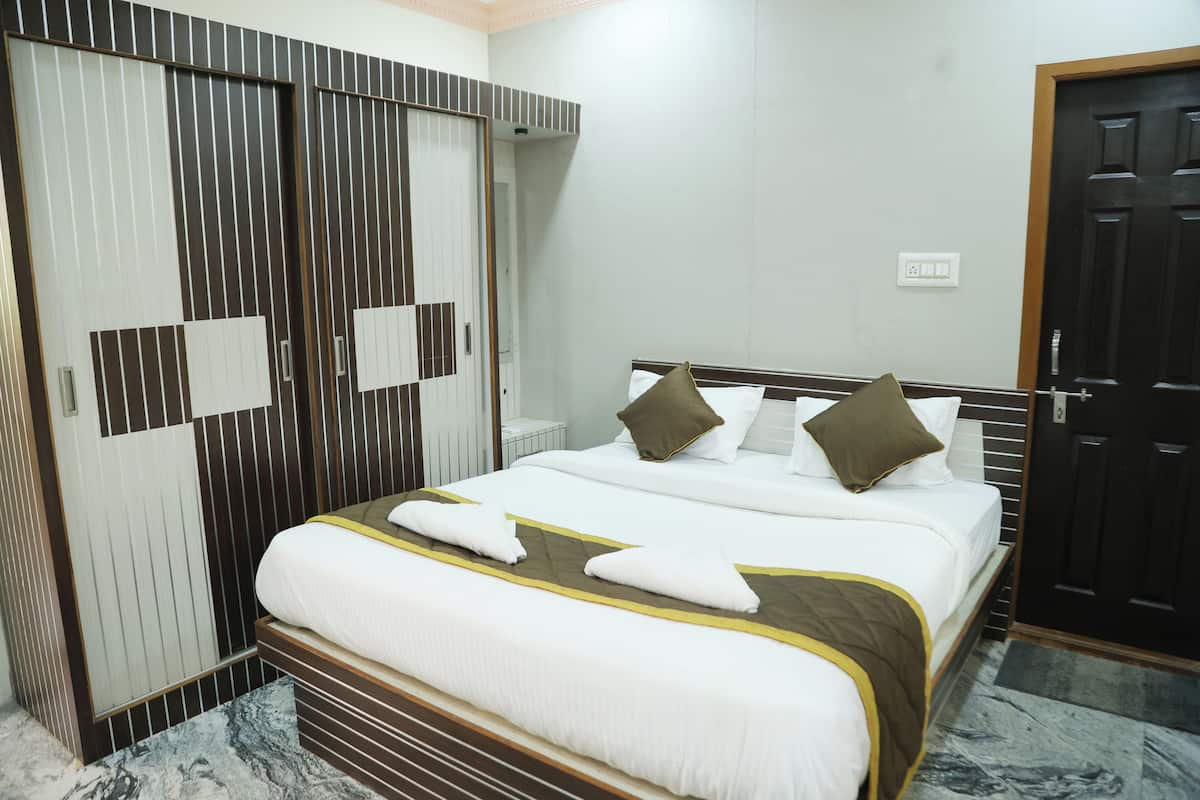 A hotel room with a large bed, a wardrobe, and a door.