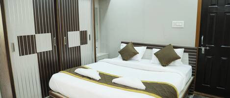 A hotel room with a large bed, a wardrobe, and a door.