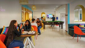 Cafetería abierta las 24 horas con mesa de billar, zonas de estar y un letrero de neón.