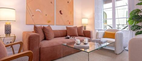 A modern living room with a sofa, glass coffee table, and two lamps.