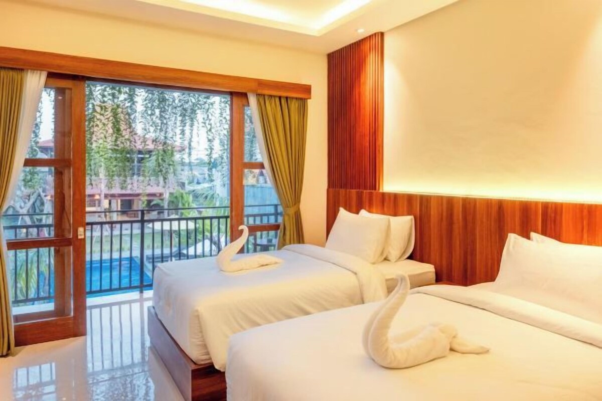 A hotel room with two beds, a balcony with a view of a swimming pool, and wooden paneling on the walls.