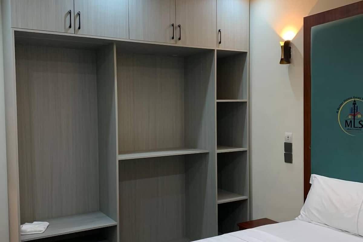 A bedroom with a large wardrobe, a bed, and a wall-mounted light fixture.