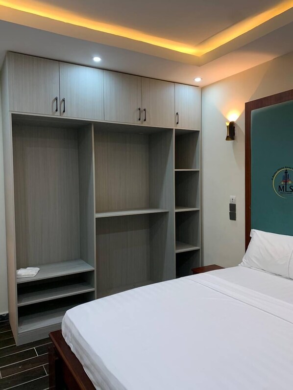 A bedroom with a large wardrobe, a bed, and a wall-mounted light fixture.
