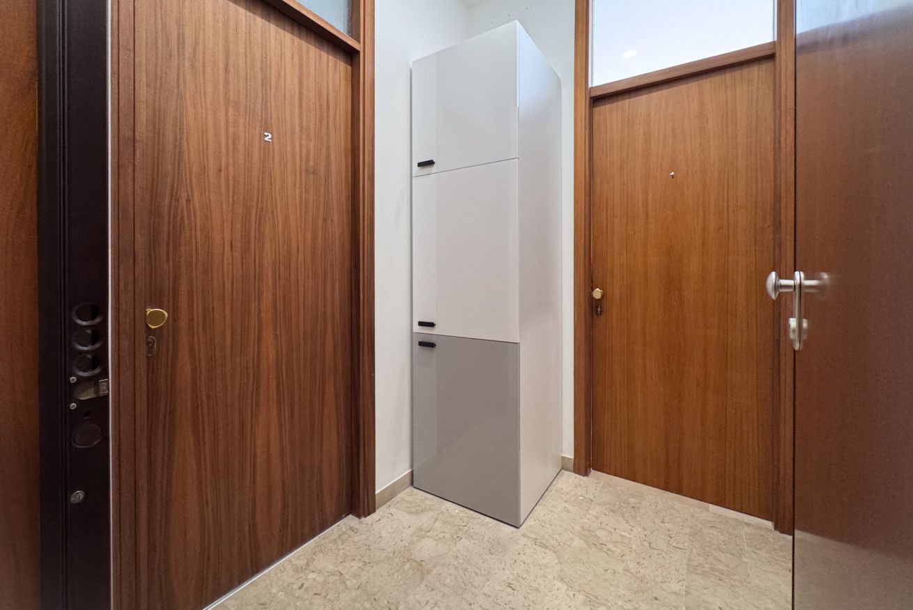 Una habitación con armarios de madera, una puerta blanca y un piso de mármol.