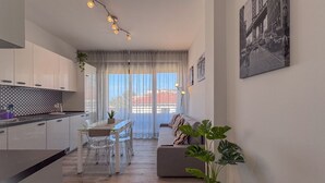 Una cocina moderna con zona de comedor, sofá y un amplio ventanal con cortinas.