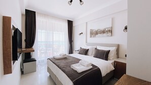 A hotel room with a bed, a TV, a window with curtains, and a painting on the wall. - THE PİER OF URLA (Urla)