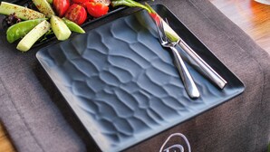 A table set with various dishes, including a plate of sliced vegetables, cheese, and bread, with a logo for "The Pier of URLA Restaurant" on the tablecloth. - THE PİER OF URLA (Urla)
