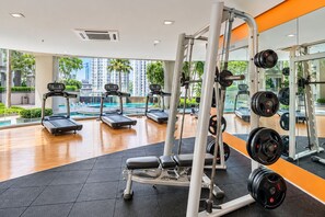 Une salle de sport équipée de tapis de course, d’appareils de musculation et de poids libres.