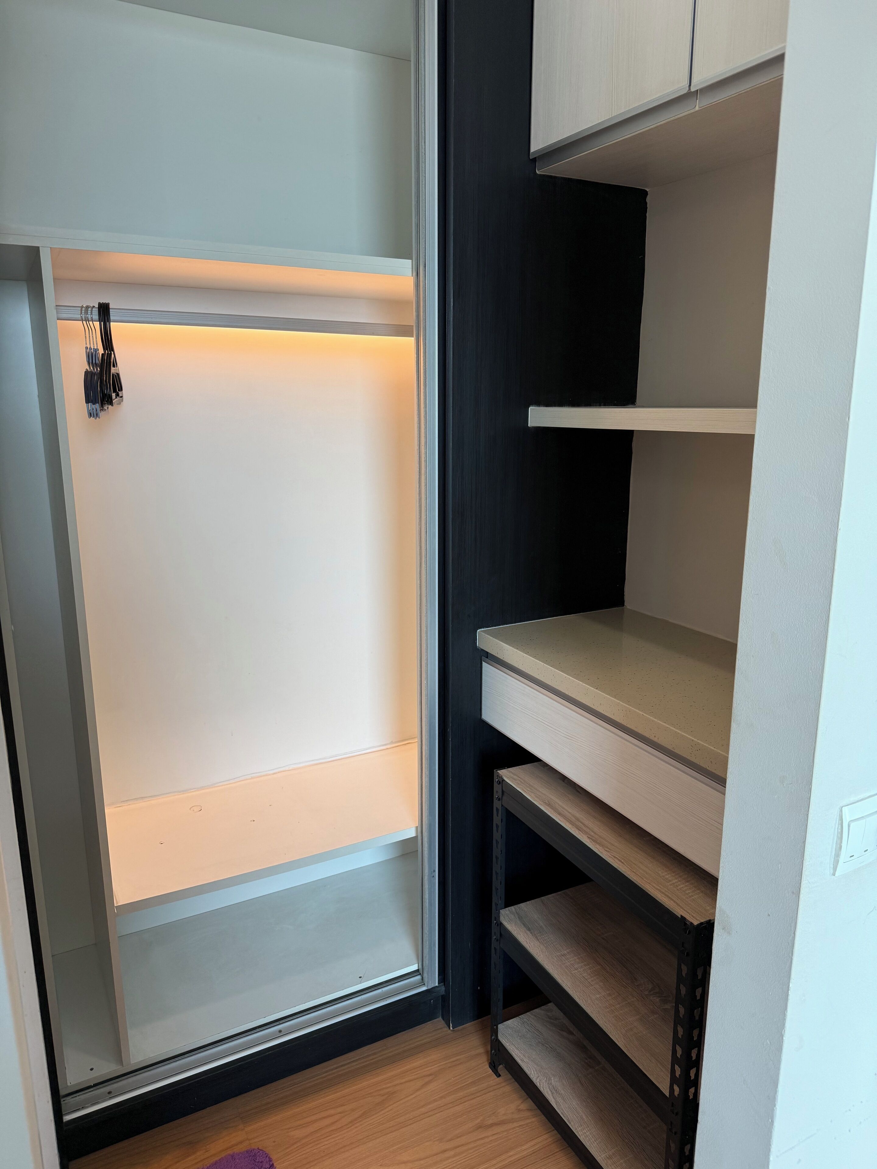 A walk-in closet with a sliding door, built-in shelves, and a wooden floor.