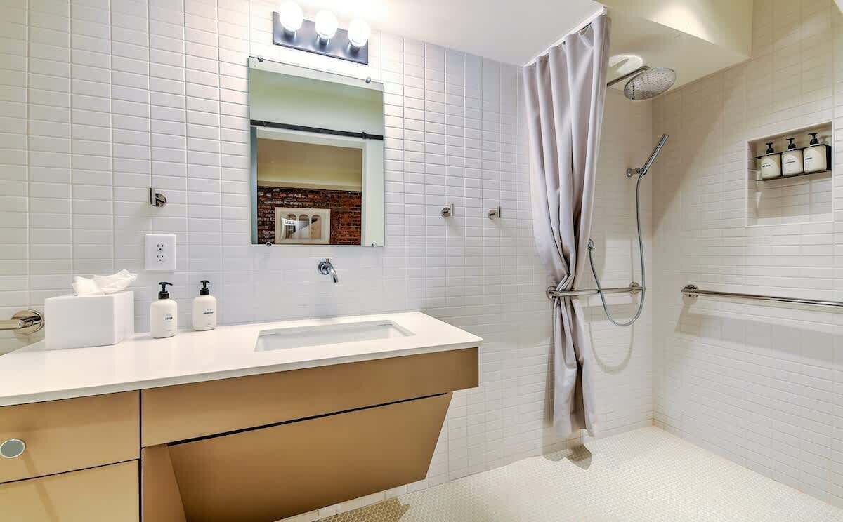 Ein modernes Badezimmer mit Waschbecken, Spiegel und Dusche in Weiß.