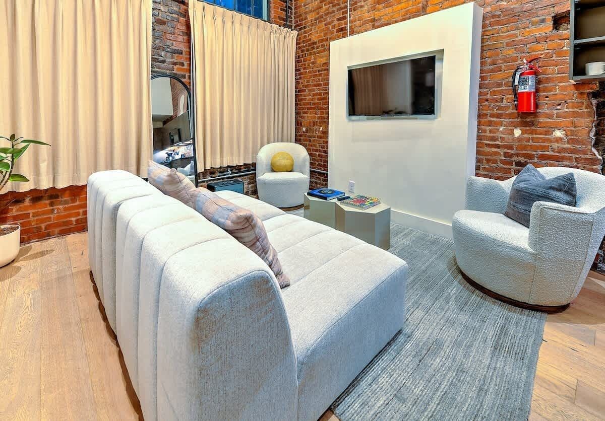 Ein modernes Wohnzimmer mit Backsteinwand, einem weißen Sofa, einem runden Sessel und einem kleinen Couchtisch.