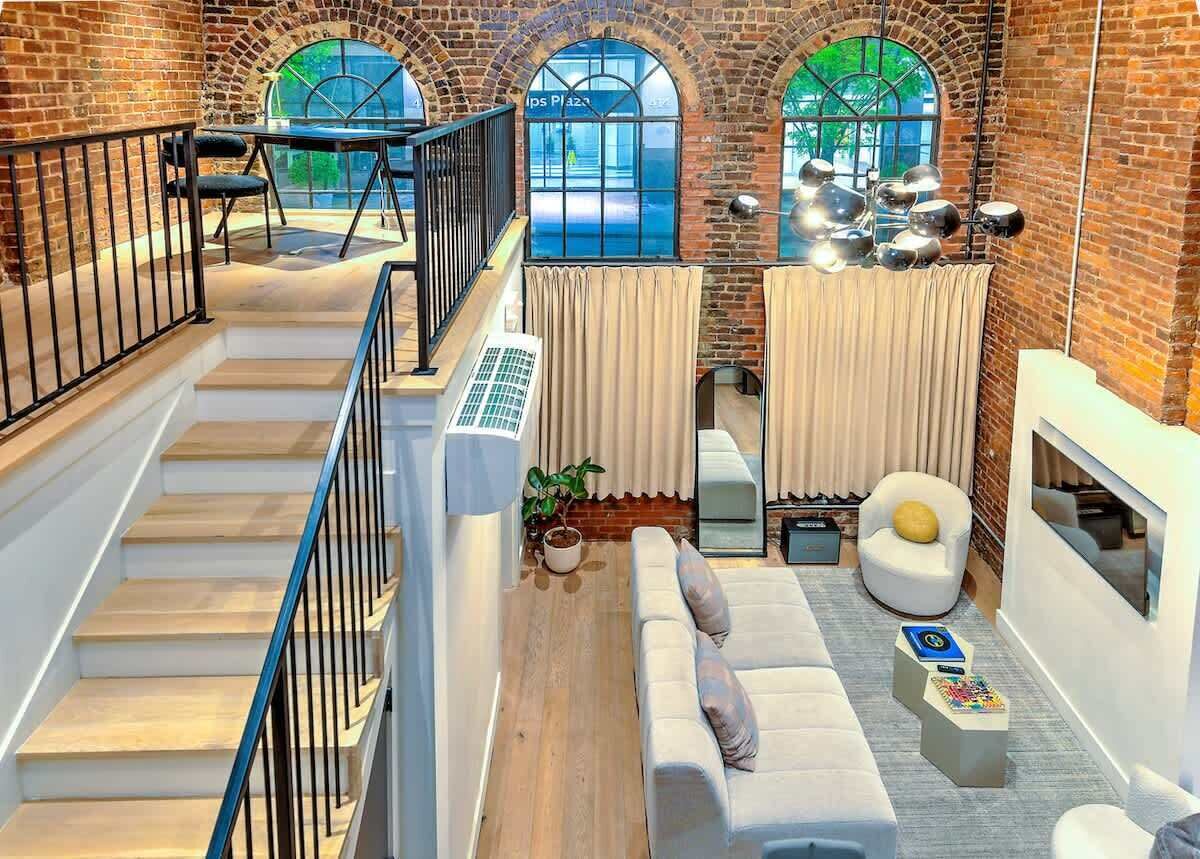 Un loft amplio con una escalera, un conjunto de sofás y un comedor.