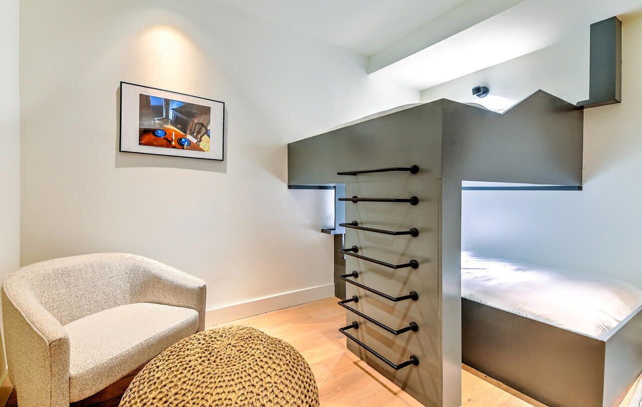Un dormitorio moderno con una litera, una silla y un estante en la pared.