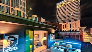 Un hôtel moderne doté d’un bar sur le toit, avec des places assises en plein air et une vue sur le paysage urbain illuminé la nuit.