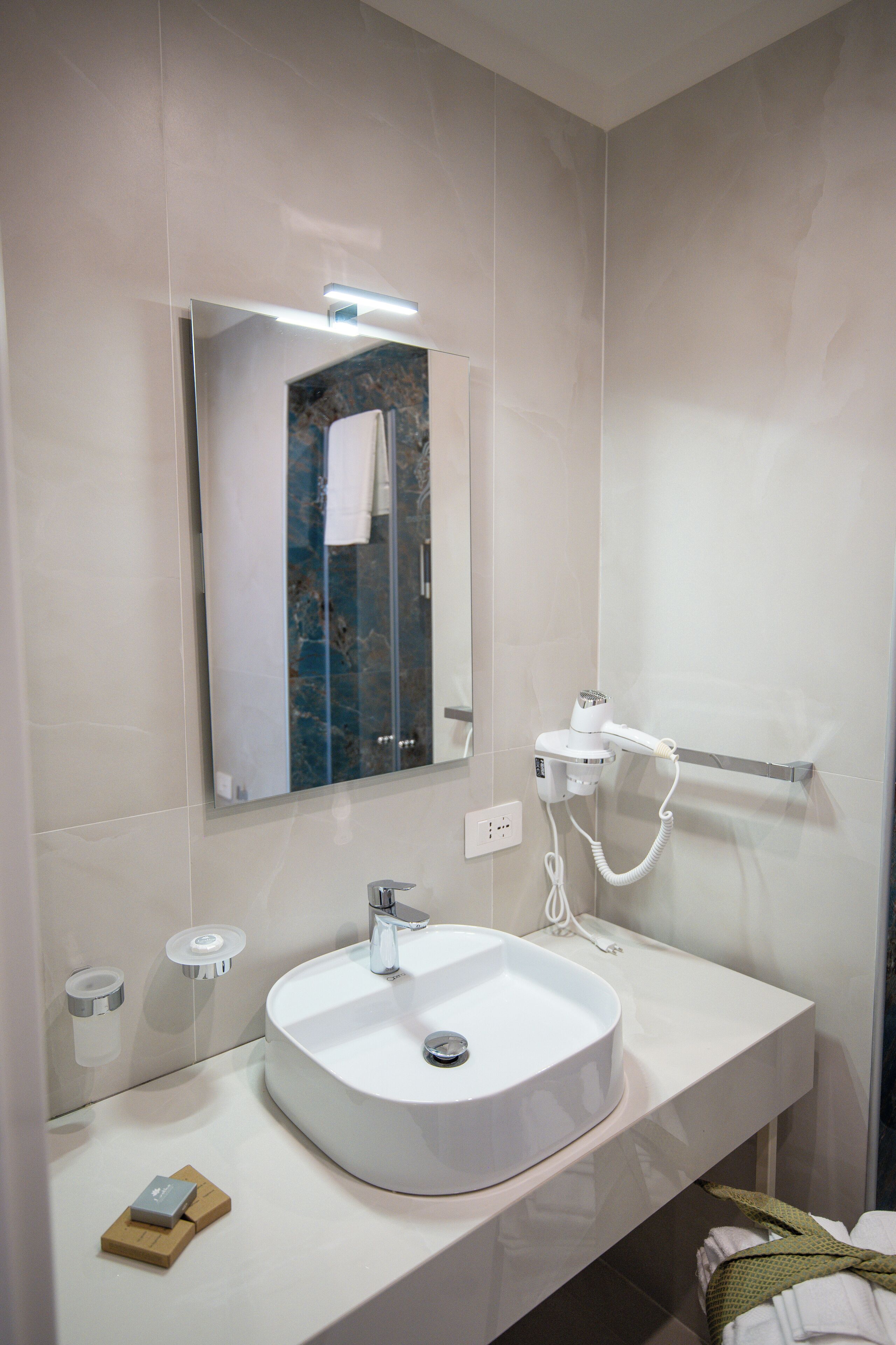 A modern bathroom with a white sink, a mirror, and a handheld showerhead.
