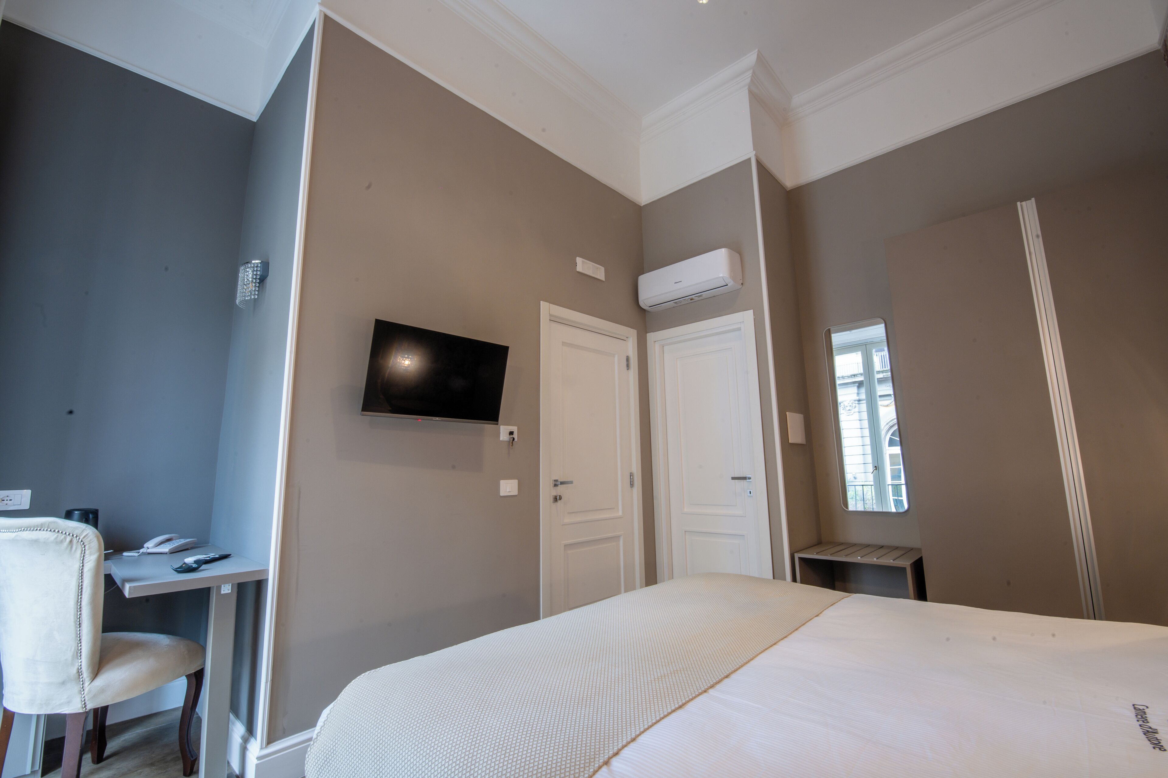 Une chambre à coucher comprenant un lit, un bureau, une chaise, une télévision et une armoire.
