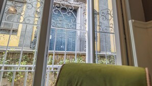 Ein Zimmer mit großem Fenster mit Blick auf ein verziertes Gebäude mit schmiedeeisernem Tor.
