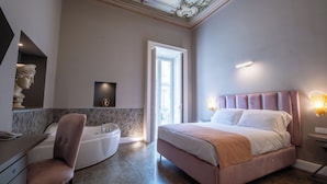Ein modernes Schlafzimmer mit einem großen Bett, einem Schminktisch mit Spiegel, einem Sessel und einer Badewanne.