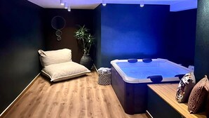 A modern spa room with a wooden floor, a massage chair, a hot tub, and a potted plant. - Acropolis Soul (Athens)