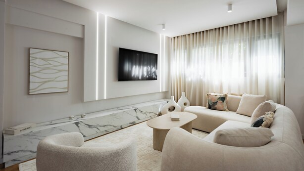 A modern living room with a marble accent wall, a flat-screen TV, a beige sofa, and a coffee table. - Acropolis Soul (Athens)